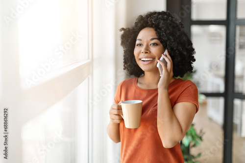 Beautiful Young Black Woman Drinking Coffee And Talking On Cellphone At Home