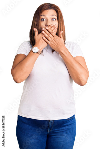 Middle age latin woman wearing casual white tshirt shocked covering mouth with hands for mistake. secret concept.