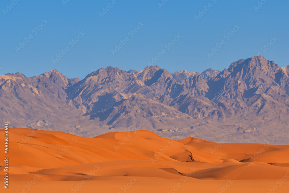 desert. large desert with orange sand, blue sky and mountains in the background. climate concept