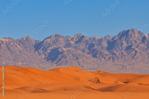 desert. large desert with orange sand, blue sky and mountains in the background. climate concept