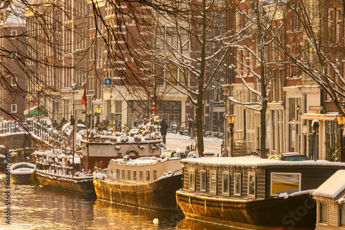 Winter view of Amsterdam with snow and house boats during sunset photo