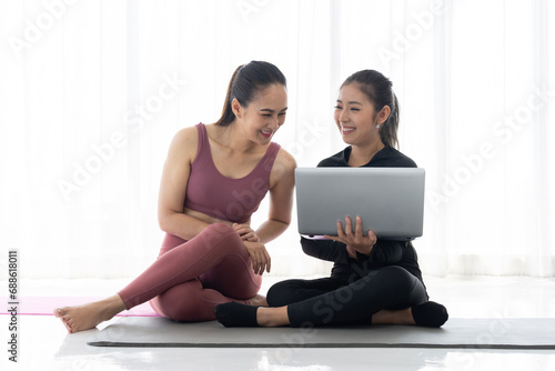 Two Asian Women Looking at laptop Together After Workout