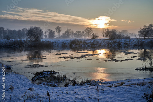floes on the Warta River and snow-covered bushes and trees during winter evening