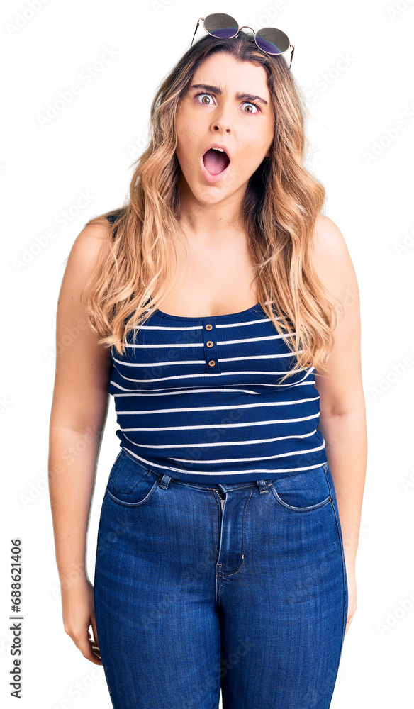 Young caucasian woman wearing casual clothes and sunglasses scared and amazed with open mouth for surprise, disbelief face Young caucasian woman wearing casual clothes and sunglasses scared and amazed with open mouth for surprise, disbelief face