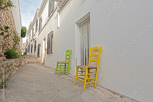 Green and yellow chairs outside the house in the white street of white andalusian village white