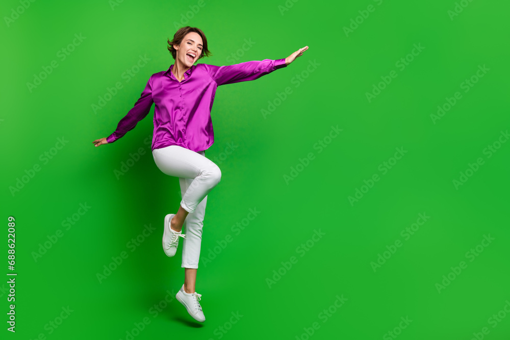 Full length portrait of overjoyed lovely person jumping flying empty space ad isolated on green color background Full length portrait of overjoyed lovely person jumping flying empty space ad isolated on green color background
