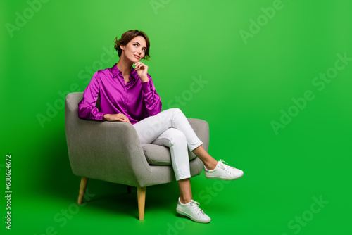 Photo of minded stunning lady professional chief sit cozy chair look up empty space offer banner isolated on green color background