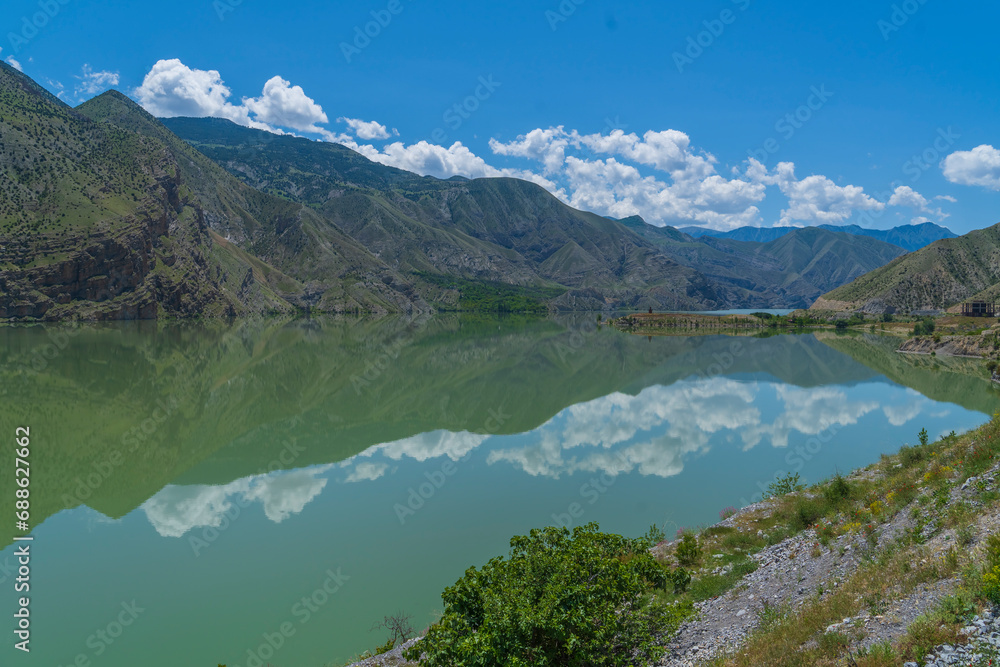 reflection of mountains in the lake and white clouds in the blue sky