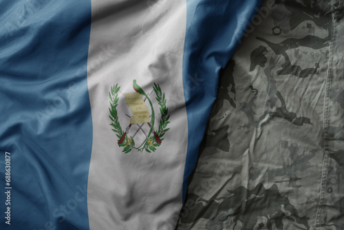 waving flag of guatemala on the old khaki texture background. military concept. photo