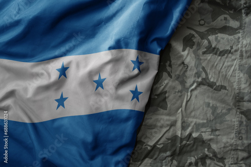 waving flag of honduras on the old khaki texture background. military concept.