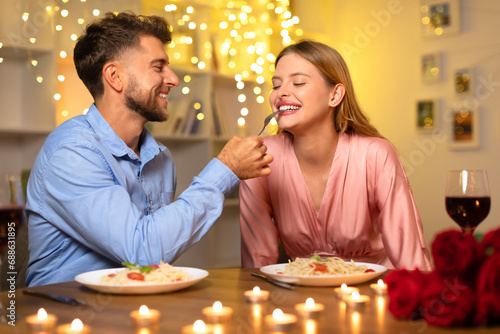 Man feeding woman pasta on romantic date
