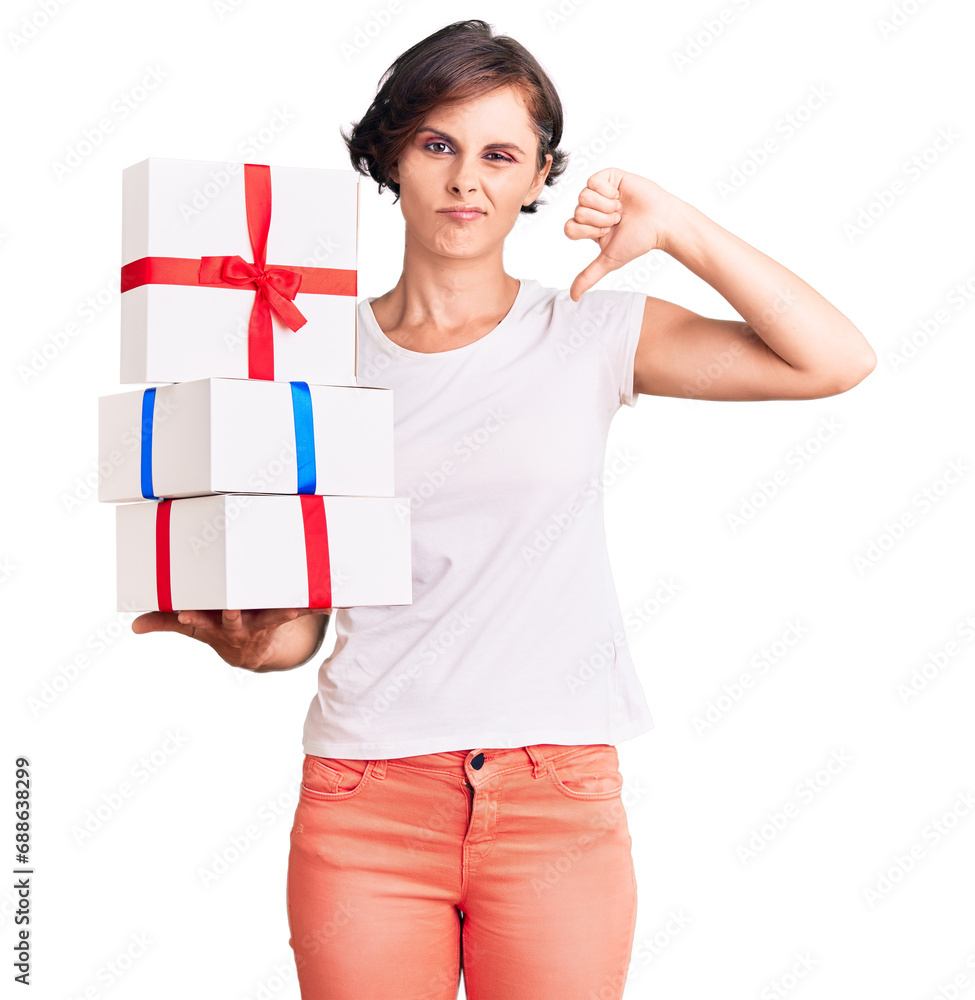 Beautiful young woman with short hair holding gifts with angry face, negative sign showing dislike with thumbs down, rejection concept Beautiful young woman with short hair holding gifts with angry face, negative sign showing dislike with thumbs down, rejection concept