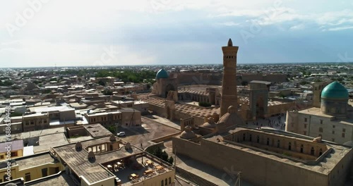 A drone flies over the tower of an ancient complex Kalyan Minaret on a sunny, cloudy day. Old Bukhara, Uzbekistan. photo