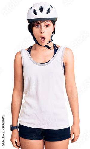 Beautiful young woman with short hair wearing bike helmet scared and amazed with open mouth for surprise, disbelief face © Krakenimages.com