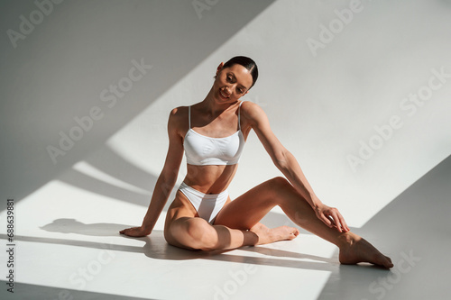 Taking a rest, with sunlight. Woman in white underwear against white background