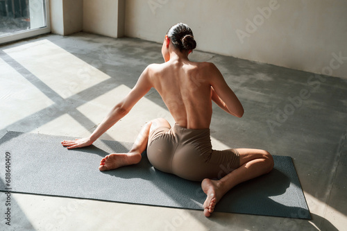 In the sunlight. Back view of sporty woman that is without bra indoors