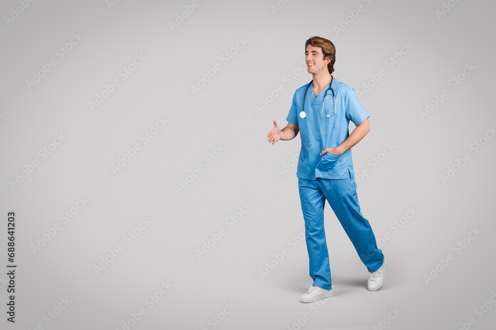 Walk-and-talk male nurse in blue scrubs on neutral grey background