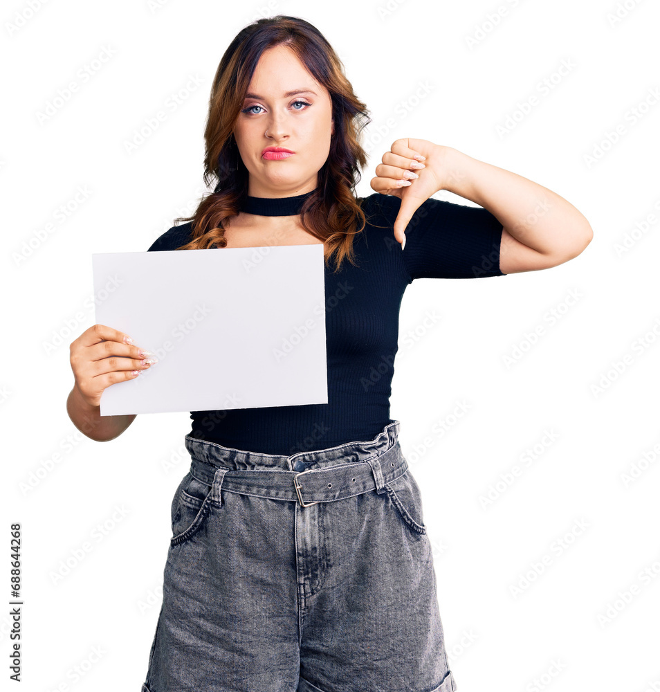 Young beautiful caucasian woman holding blank empty paper with angry face, negative sign showing dislike with thumbs down, rejection concept Young beautiful caucasian woman holding blank empty paper with angry face, negative sign showing dislike with thumbs down, rejection concept