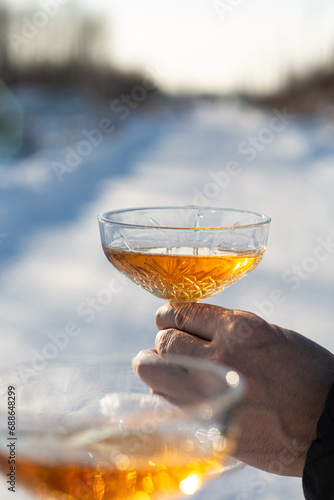 A man and a woman with glasses of champagne on a background of snow