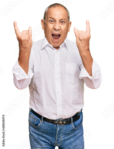 Handsome senior man wearing elegant white shirt shouting with crazy expression doing rock symbol with hands up. music star. heavy concept.