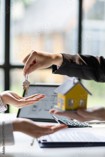 Real estate agents agree to buy a home and give keys to clients after signing contract agreement in office, moving home or renting property.