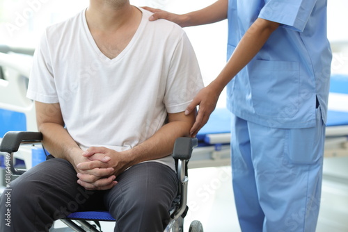 Doctor is inquiring about the condition of a patient with a leg injury in a hospital examination room. Nurse caring for the condition of a man in a wheelchair in a hospital.