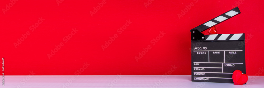 Naklejka premium Romantic date on Valentine's Day February 14. Love movie marathon, date at cinema theater. Clapperboard, popcorn buckets, heart decor and chocolates on red background flat lay copy space