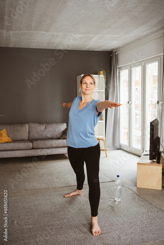 Blonde 30-Year-Old Woman Finding Serenity in Warrior Pose during Home Yoga Session
