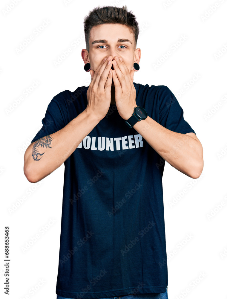 Young caucasian boy with ears dilation wearing volunteer t shirt laughing and embarrassed giggle covering mouth with hands, gossip and scandal concept Young caucasian boy with ears dilation wearing volunteer t shirt laughing and embarrassed giggle covering mouth with hands, gossip and scandal concept