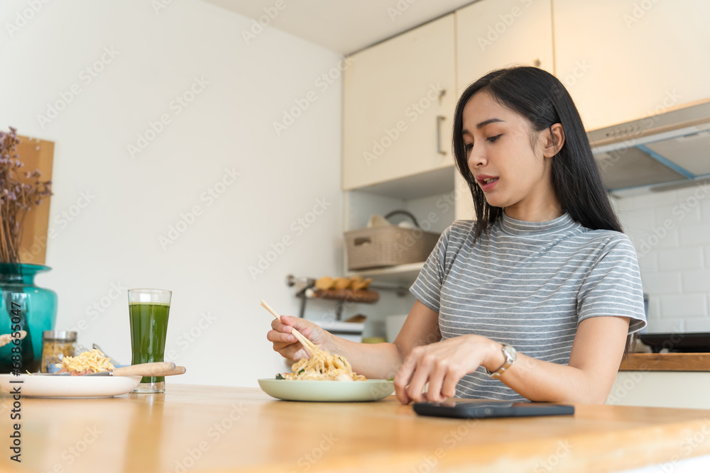 Asian Girl eating Thai food in kitchen counter Home delivery food feeling happy Asian Girl eating Thai food in kitchen counter Home delivery food feeling happy