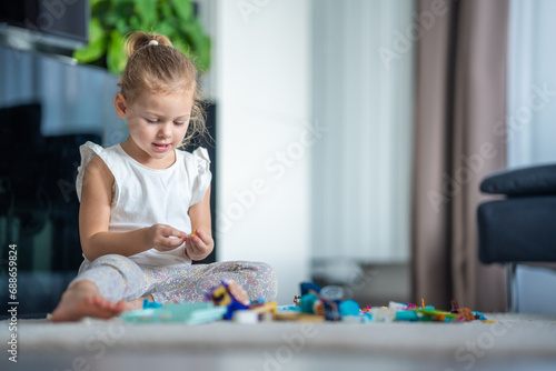 Little girl play with small constructor toy on floor in home living room, educational game, spending leisure activities time concept