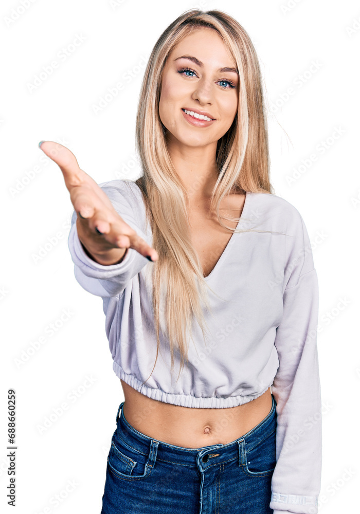 Beautiful young blonde woman wearing casual white sweater smiling friendly offering handshake as greeting and welcoming. successful business. Beautiful young blonde woman wearing casual white sweater smiling friendly offering handshake as greeting and welcoming. successful business.