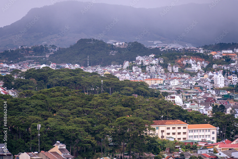 Obraz premium View on roofs in the city of Dalat. Da Lat and the surrounding area is a popular tourist destination of Asia. City with fogs and mountains