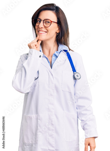 Young beautiful woman wearing doctor stethoscope and glasses looking confident at the camera with smile with crossed arms and hand raised on chin. thinking positive.