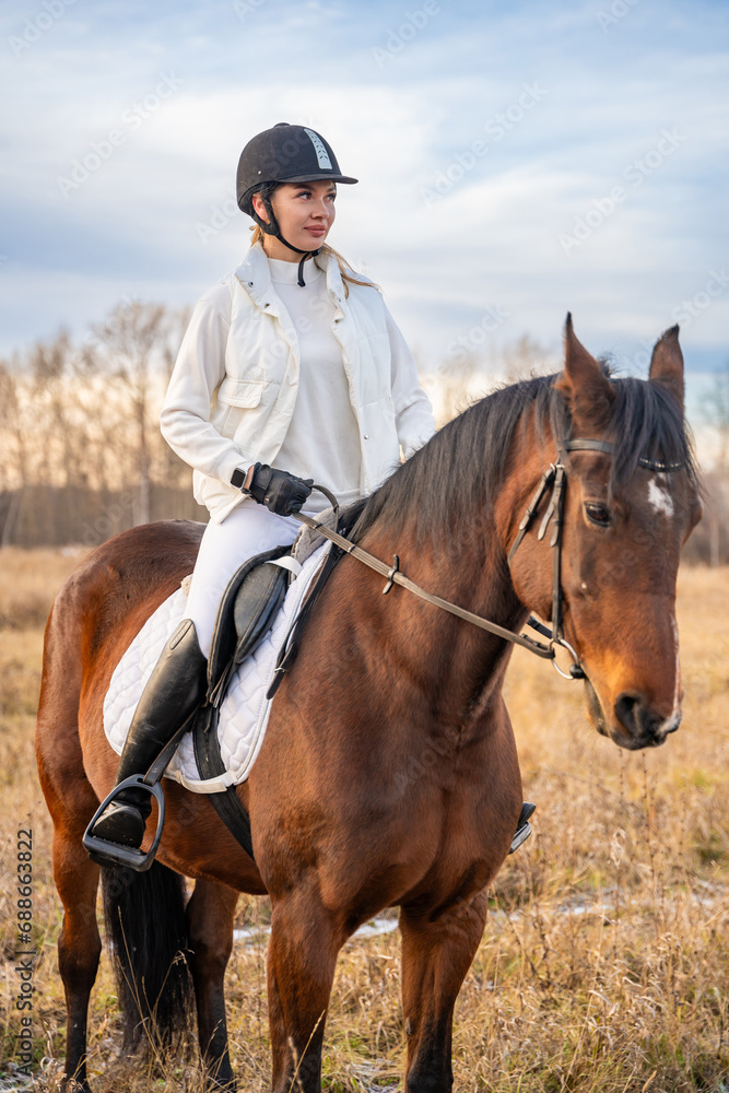 Fototapeta premium Beautiful blond professional female jockey riding a horse