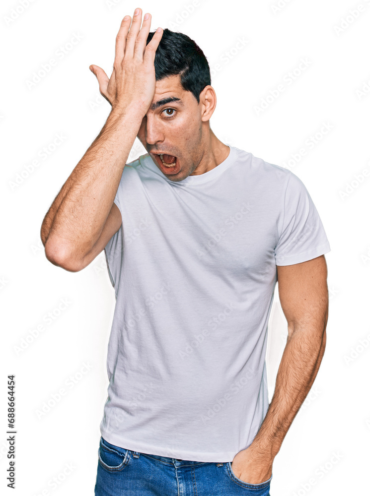 Handsome hispanic man wearing casual white t shirt surprised with hand on head for mistake, remember error. forgot, bad memory concept. Handsome hispanic man wearing casual white t shirt surprised with hand on head for mistake, remember error. forgot, bad memory concept.