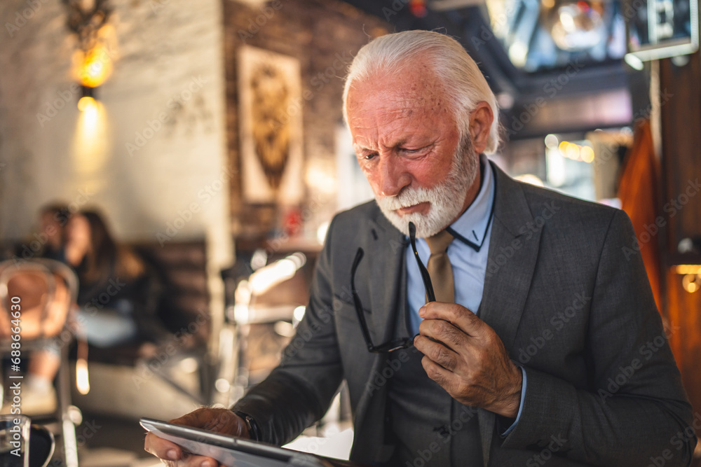 Senior man businessman business owner use digital tablet sit at cafe Senior man businessman business owner use digital tablet sit at cafe