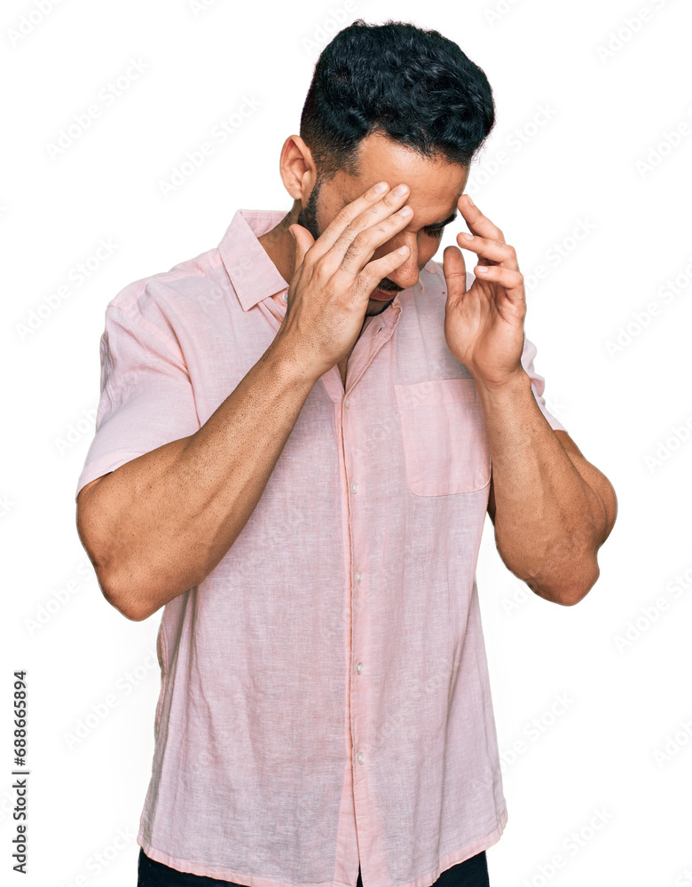 Hispanic man with beard wearing casual shirt with hand on head for pain in head because stress. suffering migraine. Hispanic man with beard wearing casual shirt with hand on head for pain in head because stress. suffering migraine.