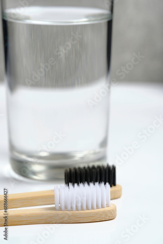 Glass water and two wooden toothbrushes bathroom on a white background.