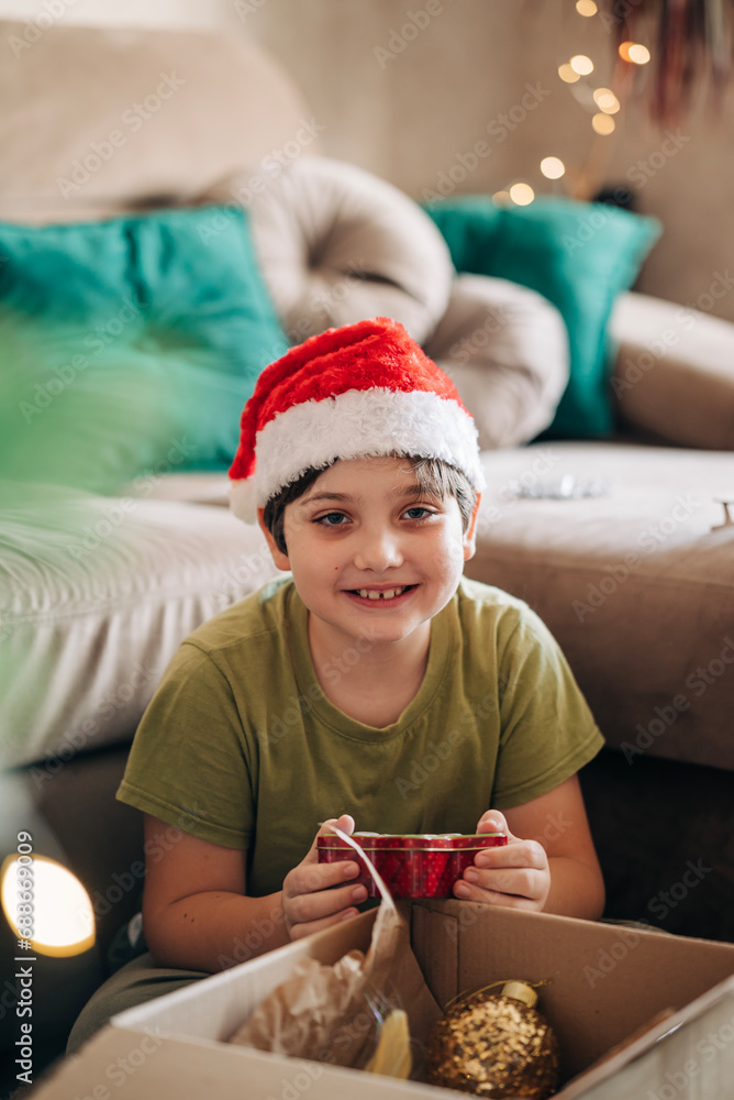 Kid boy decorating Christmas tree put off balls from the box authentic real celebration image lifestyle. Xmas with family children fun at cozy home Kid boy decorating Christmas tree put off balls from the box authentic real celebration image lifestyle. Xmas with family children fun at cozy home