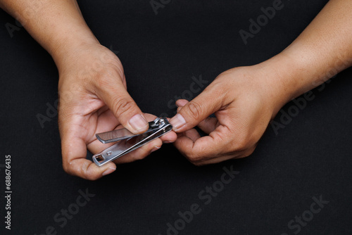 Males's hand holding on nail clippers, man use nail clipper cutting their thumbs nail. © Haeruman