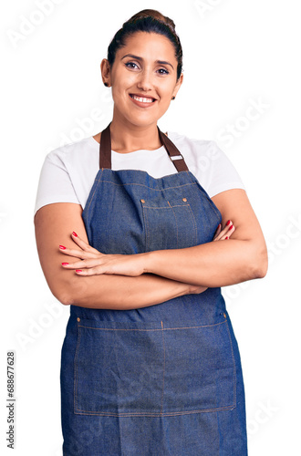 Foto Young beautiful brunette woman wearing apron happy face smiling with crossed arms looking at the camera