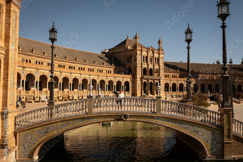 lady on a bridge outside The National Geographic Institute in Plaza de España Seville city Spain. Central government offices in stunning rich wealthy architecture design on sunny day.  © drew