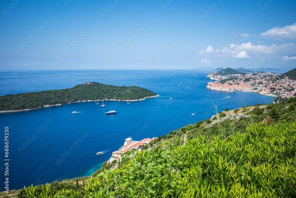 Top view to Dubrovnik Old Town and Lokrum island in the Adriatic sea on sunny summer day. Focus on green bushes in the foreground
