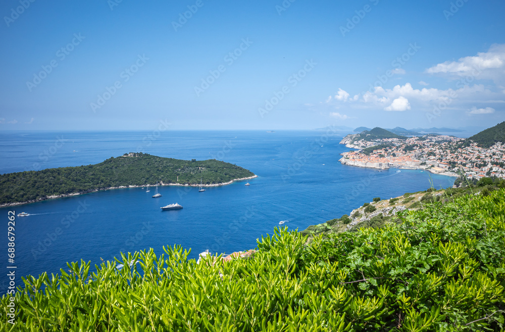 Top view to Dubrovnik Old Town and Lokrum island in the Adriatic sea on sunny summer day. Focus on green bushes in the foreground Top view to Dubrovnik Old Town and Lokrum island in the Adriatic sea on sunny summer day. Focus on green bushes in the foreground