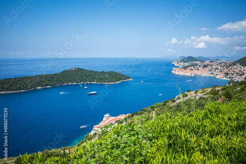 Top view to Dubrovnik Old Town and Lokrum island in the Adriatic sea on sunny summer day. Focus on green bushes in the foreground 