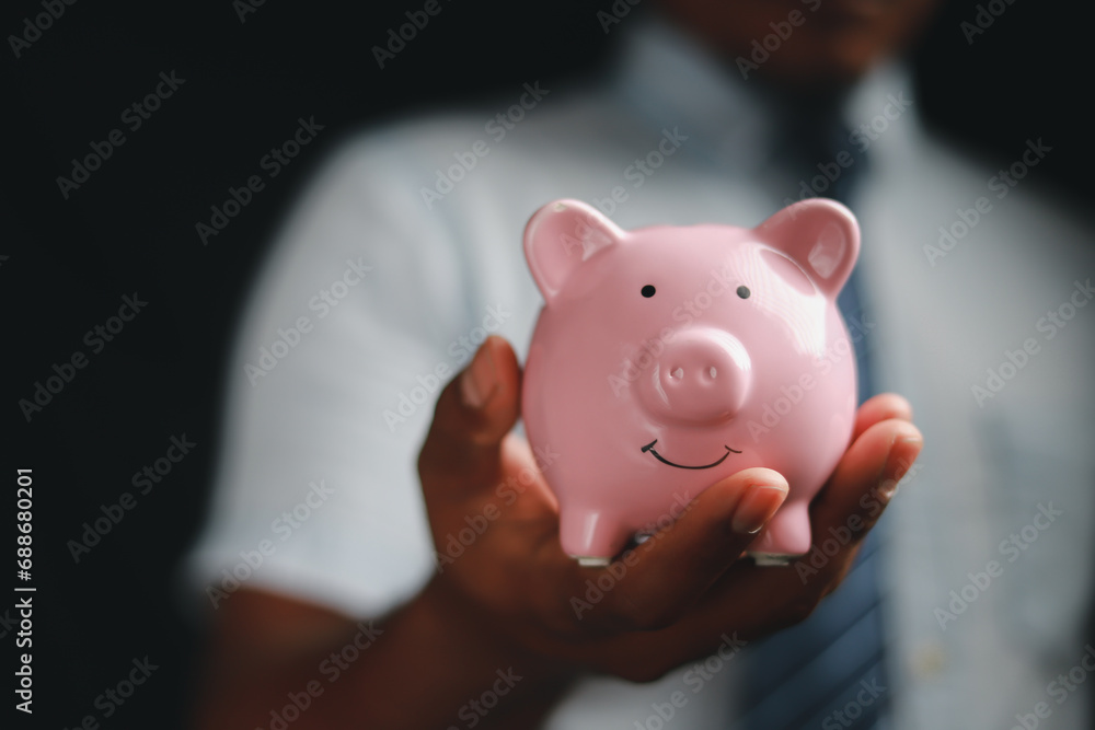Financial concept, man holding piggy bank on wooden table Financial concepts, business, finance, investing, financial planning, investing for education Financial concept, man holding piggy bank on wooden table Financial concepts, business, finance, investing, financial planning, investing for education