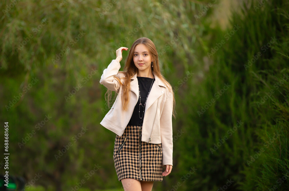 A young smiling girl walking in an autumn park in a good mood. Teenage girl, portrait against a background of nature. Fashion style trend. A young smiling girl walking in an autumn park in a good mood. Teenage girl, portrait against a background of nature. Fashion style trend.