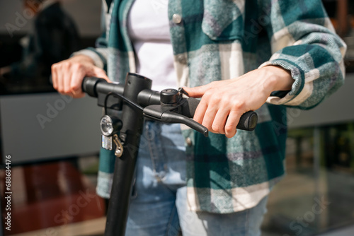 close up of woman hands in shirt with electric scooter at the urban city bottom view People lifestyle concept