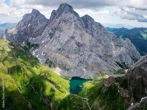 Aerial view of Volaia Lake (Wolayersee) in the border of Italy and Austria with Coglians mountain in the background. Cloudy day with some sun opening. Vibrant colors. Beautiful destinations for hikers